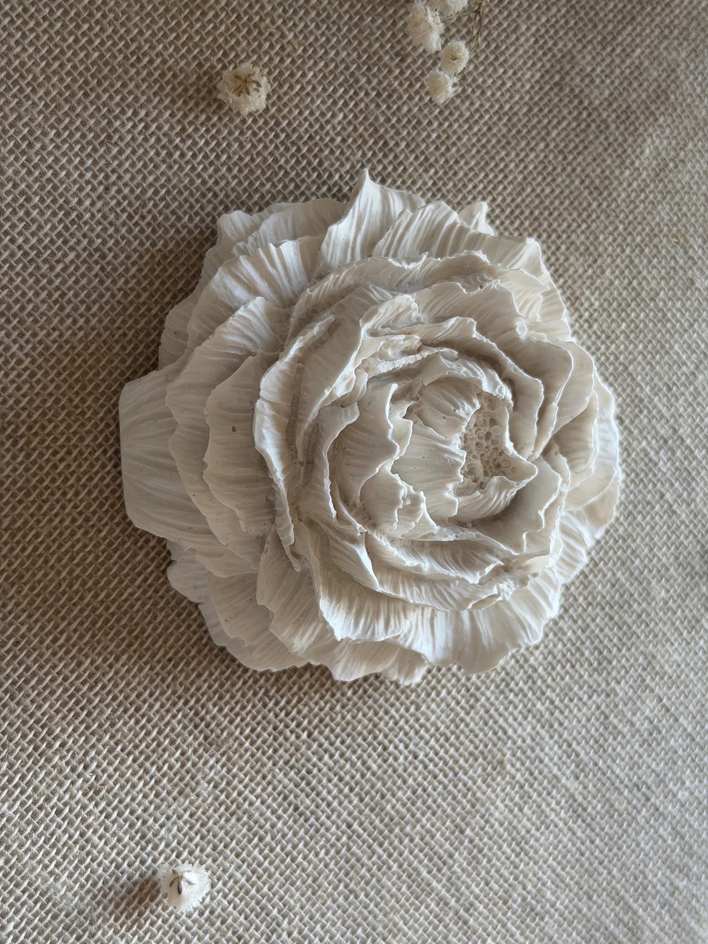 White ceramic flower on a textured beige surface