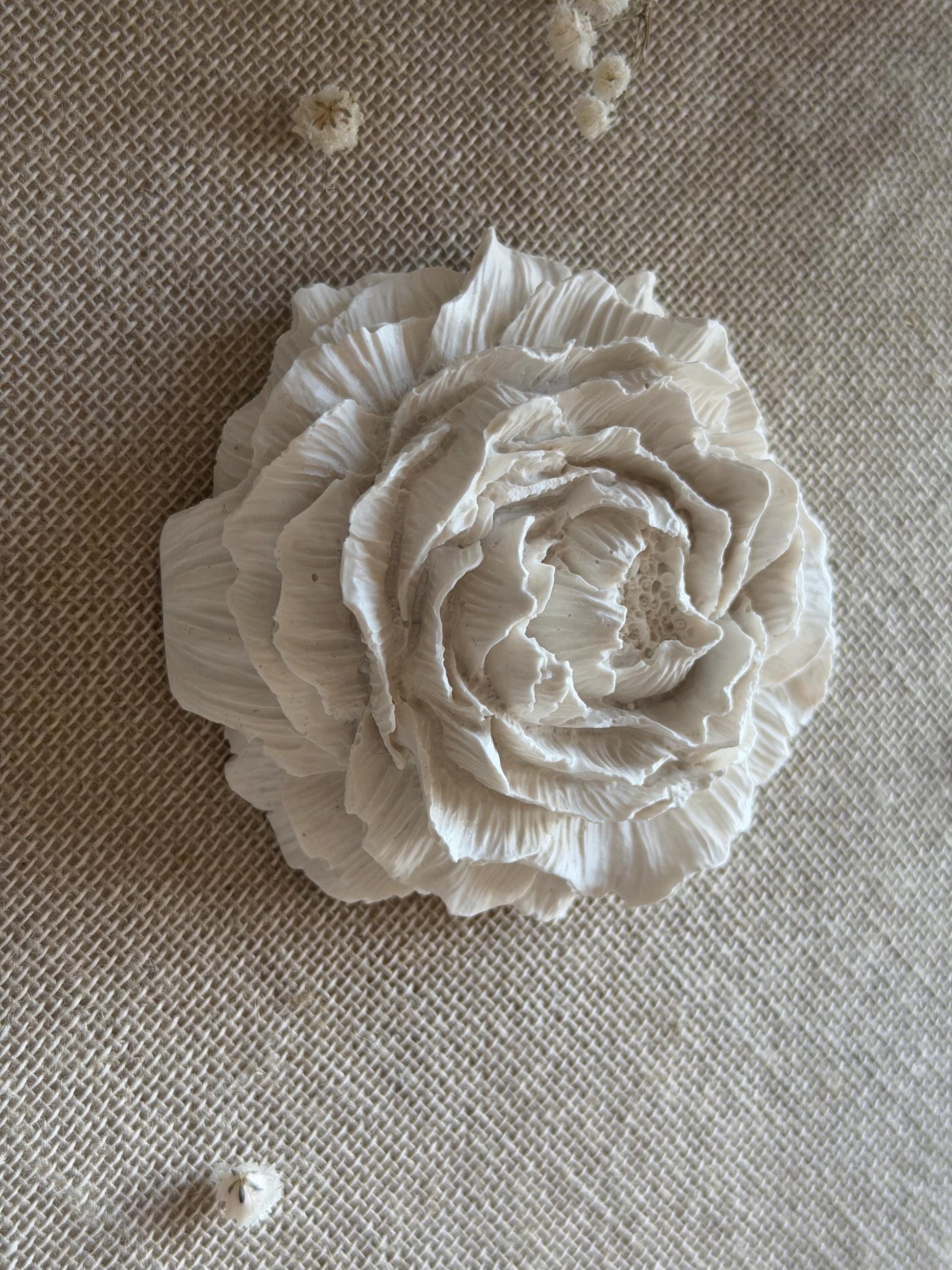 White ceramic flower on a textured beige surface
